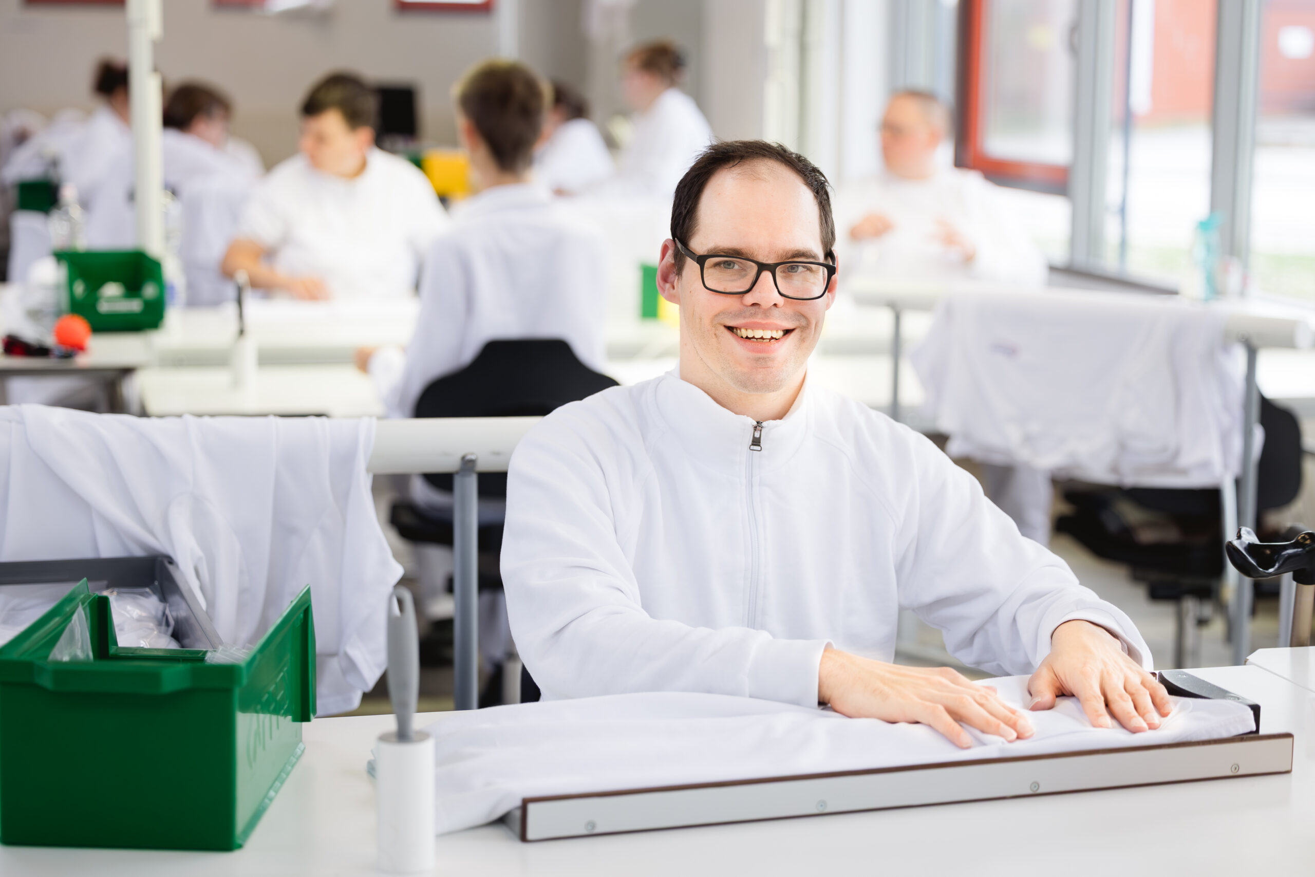 Portrait: Christoph. Ein Mann mit braunen Haaren und Brille faltet lächelnd Kleidung.